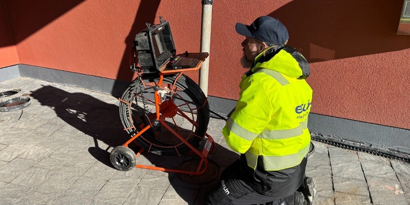 Jani suorittamassa salaojakuvausta punaisen omakotitalon pihalla.