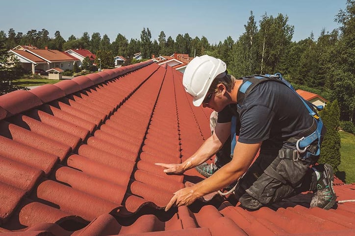 Serlinin ammattilainen vaihtamassa rikkinäistä kattotiiltä.